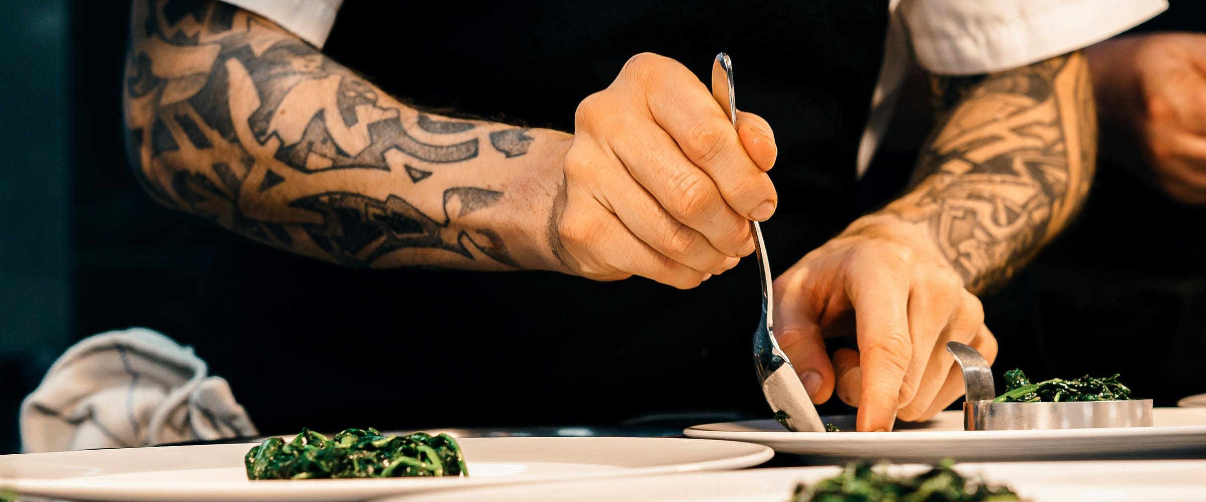 Two chefs plating dishes on the pass during service